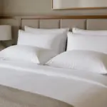 Cama de hotel con dos almohadas blandas y dos firmes sobre ropa de cama blanca