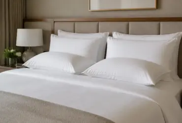 Cama de hotel con dos almohadas blandas y dos firmes sobre ropa de cama blanca