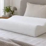 Almohada cervical contorneada con dos alturas sobre una cama
