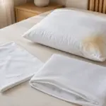 Almohada con manchas amarillas junto a una funda y un protector limpios